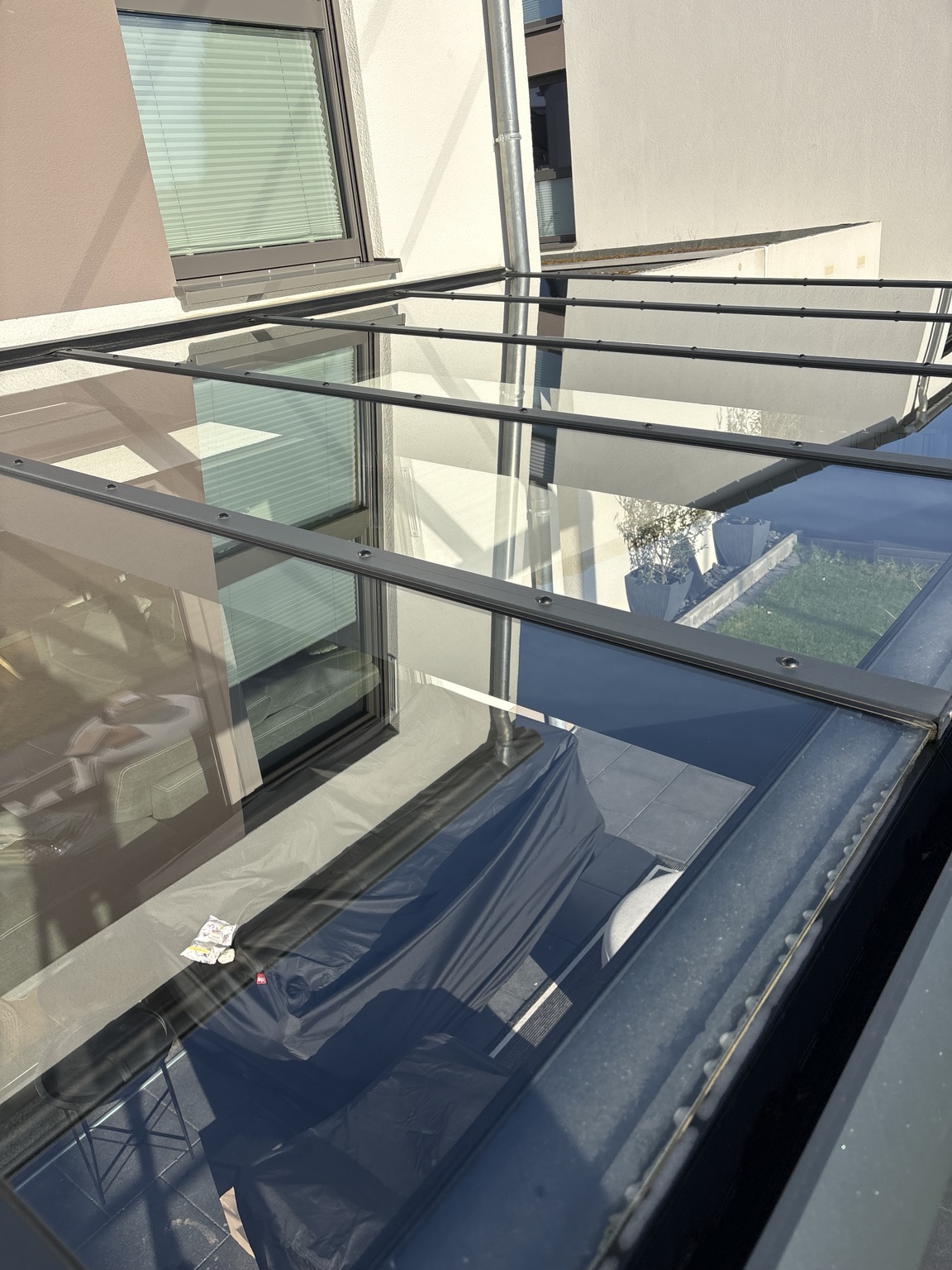 Terrassenglasdach mit dunklen Trägern und Spiegelungen